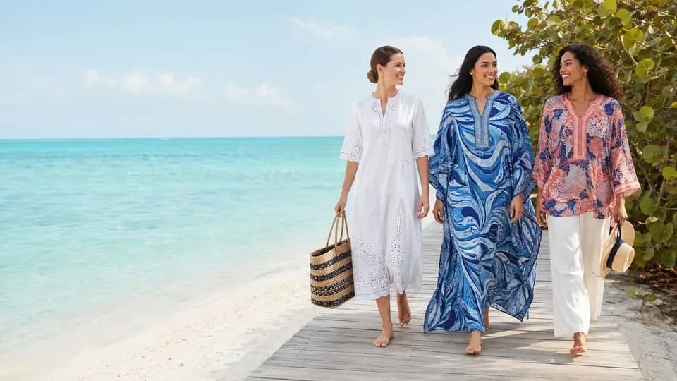 Three women in kaftans and cover-ups walking a beach boardwalk in Grand Cayman